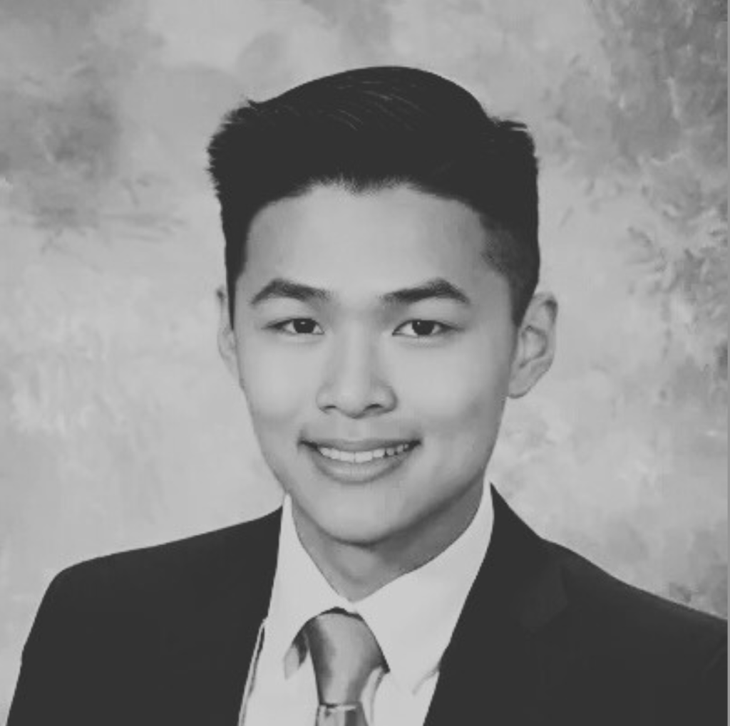 Black and white headshot of a young man in a suit.